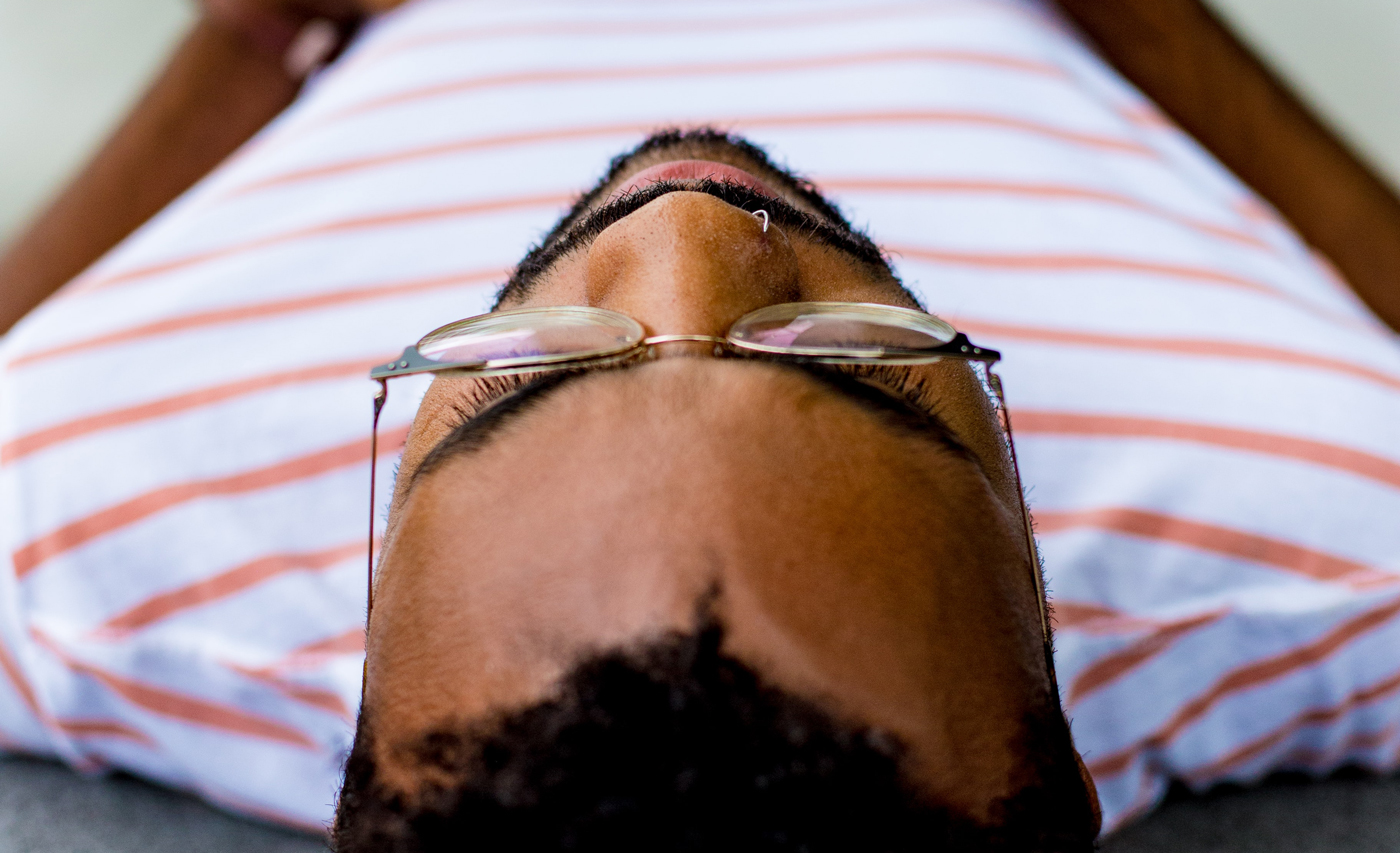 A man wearing glasses lies down facing away from the camera