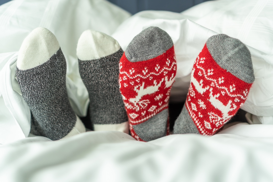 Family wearing Christmas socks relaxing on a bed, symbolizing restful sleep and cozy holiday moments in a festive bedroom.