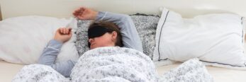 A 50-year-old woman is comfortably sleeping in her bed with a sleep mask on.